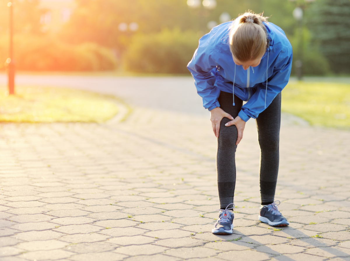 Femal runner grabbing injured knee in pain